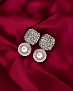 Close-up of a gold and pearl jewelery set placed on silk fabric